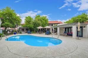 This inviting backyard boasts a sparkling swimming pool, perfect for spending hot summer days. The comfortable chairs and umbrellas provide a place to relax and unwind.
