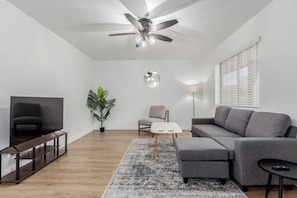 Relax in style with a comfy sofa, smart TV, and big windows that fill the room with natural light — perfect for movie nights or lazy mornings.