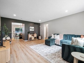 Spacious and stylish living room with a plush sectional, soft lighting, and warm wood floors 🌿🛋️. Perfect for movie nights or lounging with loved ones—plus a direct view into the elegant dining area! 🍷✨