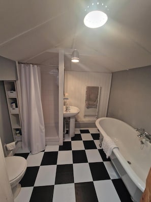 full bathroom with shower and roll top bath