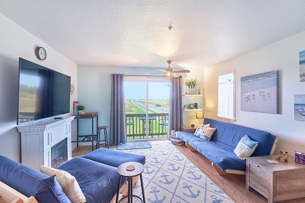 Cozy beach-themed living space features a wall-mounted TV, nautical decor, and a comfortable seating area.
