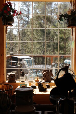 View of connected deck with gas grill and griddle with dining table and bench.