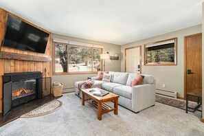 The living area boasts a warm electric fireplace, a smart TV , and comfortable seating . The couch converts into a Queen sofa sleeper for additional sleeping for two people.