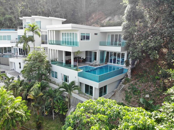 a luxurious multi-level villa nestled in a lush tropical hillside. 