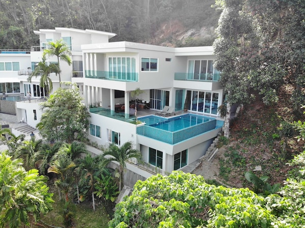 a luxurious multi-level villa nestled in a lush tropical hillside.
