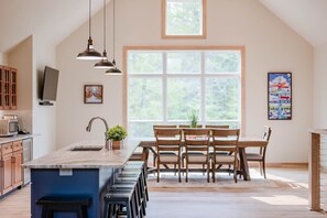 Kitchen island features the sink with pendant lighting. There is a wine refrigerator and a microwave for your use. Dining room table seats 8 while the island seats 8 as well. 