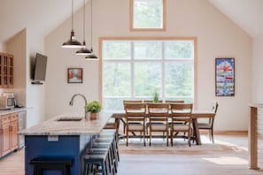 Kitchen island features the sink with pendant lighting. There is a wine refrigerator and a microwave for your use. Dining room table seats 8 while the island seats 8 as well.