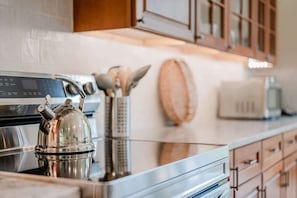 Glass top stove with tea kettle. Kitchen is fully stocked with everything you need to cook including all the utensils you will need. It has a full set of pots and pans, glassware, silverware, and kitchen towels.