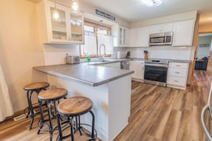 Three kitchen stools line the counter in the full kitchen, offering comfortable seating for casual meals or conversation. The perfect spot for guests to gather, whether enjoying breakfast or a cup of coffee.