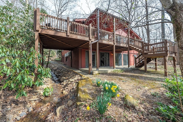 Tranquil exterior with a babbling brook running alongside the house and beneath the spacious deck