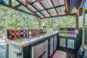 Covered outdoor bar & grill area with bar stools, cozy seating, and ambient lighting—perfect for relaxing and socializing outdoors.
