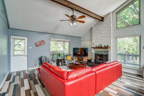 Bright living room with large windows, comfy oversized sofa, fireplace, and TV—perfect for relaxing, gathering, and enjoying natural light.