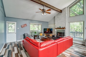 Bright living room with large windows, comfy oversized sofa, fireplace, and TV—perfect for relaxing, gathering, and enjoying natural light.