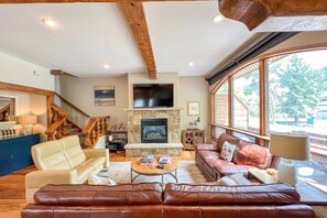 Warmth and comfort await in the inviting living room, complete with a gas fireplace, large flatscreen TV, and stunning wood beams.