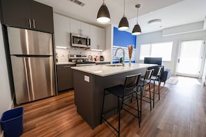 Discover the allure of an open kitchen design, complemented by a sleek bar table ideal for casual dining and entertaining experiences.