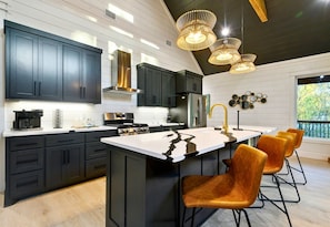The kitchen is both bold and welcoming, with rich dark cabinets, sleek countertops, and statement lighting that sets the stage for cooking, chatting, and memory-making.
