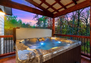 Soak your stress away in the bubbling hot tub while enjoying the quiet forest view and colorful skies—pure relaxation under the covered porch.