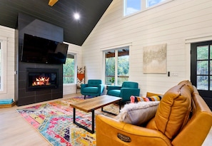 This cozy living room features high ceilings, a warm fireplace, and a vibrant rug that adds a playful pop to the neutral tones—perfect for snuggling up after a day of adventure.