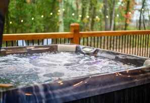 Let the soothing sounds of bubbling water and twinkling string lights melt your worries away in this inviting forest-view hot tub.