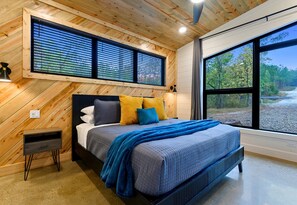 Bedroom 1 offers a serene space with warm wood ceilings, bold black framing, and huge windows to bring the outdoors in.