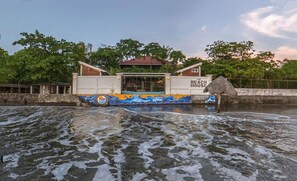Post Sunset Beach House with soft lighting and rolling waves right up to our artistically adorned breakwall.
