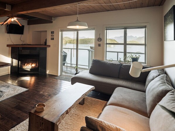 Open plan living/dining room with gas fireplace with beautiful views of the Tofino harbour