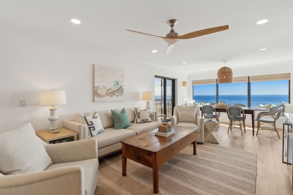 Luxury Living Area Featuring Plush Couch and Chairs, Flat Screen Smart TV, and Modern Coastal Decor