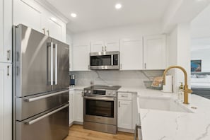Updated Kitchen with Quartz Countertops, Stainless Steel Appliances, and Large Farmhouse Style Sink