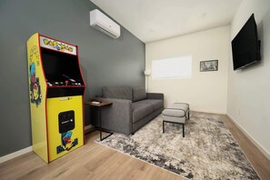 Upstairs bedroom features an open layout with a comfortable king-size pull-out bed, a classic Pac-Man arcade game, big screen tv and a dedicated workspace—perfect for productivity or play. You’ll also find a closet with extra linens, a luggage rack. 