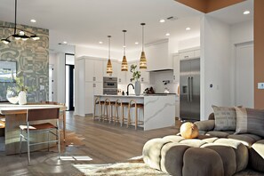 Bright and open living space seamlessly blending a modern white kitchen with a stylish dining area and a comfortable lounge, all bathed in natural light