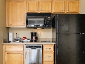 A compact and functional kitchenette with wooden cabinets, modern appliances, and essential amenities for a convenient stay.
