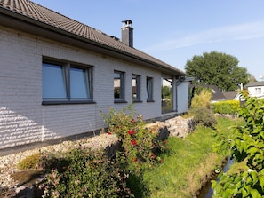 Ferienhaus Seitenansicht, daneben ein kleiner Bachlauf
