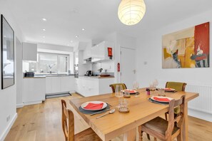 Dining area adjacent to the kitchen with a wooden table set for 5 guests