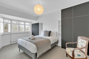 Master bedroom with a king-size bed, bedside tables, and built-in wardrobe