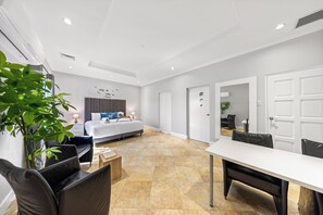 Large bedroom with king bed, workspace, seating area, and AC.
