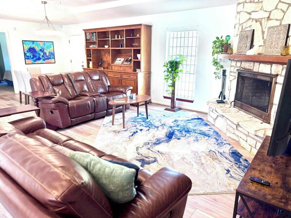 Spacious comfortable living room with cozy gas-start wood-burning fireplace and big-screen TV.