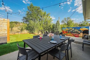 Outdoor Dining & Scenic Views! Enjoy meals with plenty of seating, a BBQ grill nearby, and a stunning mural backdrop. Perfect for evening gatherings under the string lights.!