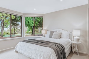 Wake up to leafy views in the second bedroom, where a queen bed and soft, neutral styling create a calming space to rest and recharge.