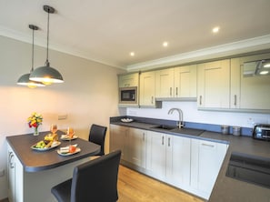 Kitchen with breakfast bar and dining stools, kitchen units, sink and hob