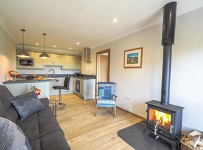 The lounge and the kitchen with a sofa, log burner, chair wooden floors.