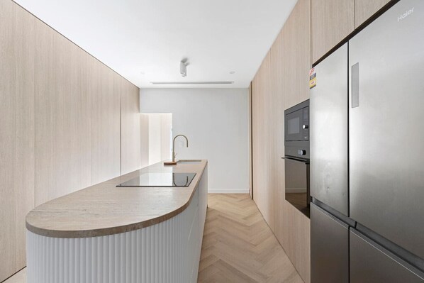 Sleek modern kitchen with high-end appliances, stylish wood finishes, and a spacious island—perfect for cooking and entertaining! By Superhostly