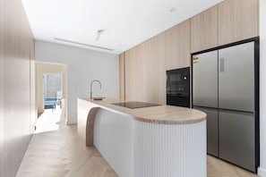 Sleek modern kitchen with high-end appliances, stylish wood finishes, and a spacious island—perfect for cooking and entertaining! By Superhostly