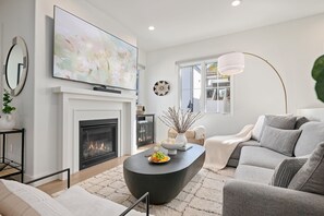 Cozy living room is anchored by the fireplace & features a large TV and sound bar.