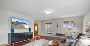 Kick back in the cozy main living area featuring plush seating, abundant natural light, and a smart TV – perfect for movie nights or morning coffee.