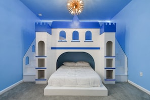 Castle-themed bedroom with bunk beds, bold blue accents, and playful design.