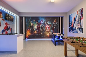 Superhero-themed game room with foosball, air hockey, and epic wall art.