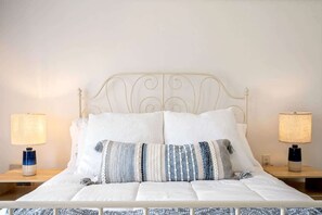 The serene bedroom area boasts a plush queen bed & balcony access