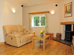 Comfy reclining sofa, coffee table with vase of flowers. Fir place and logs
