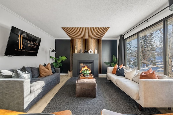 Main floor living room with a gas-lit fireplace, smart TV with cable & cozy seating options.