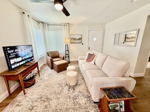 Cozy living area with smart TV, comfy seating, and open kitchen concept.